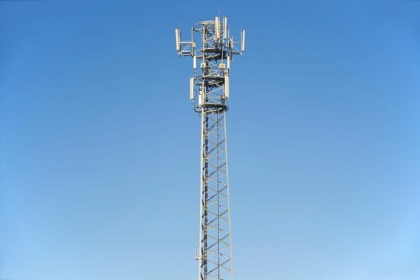 A tall cell tower set against a clear blue sky, representing modern communication technology.